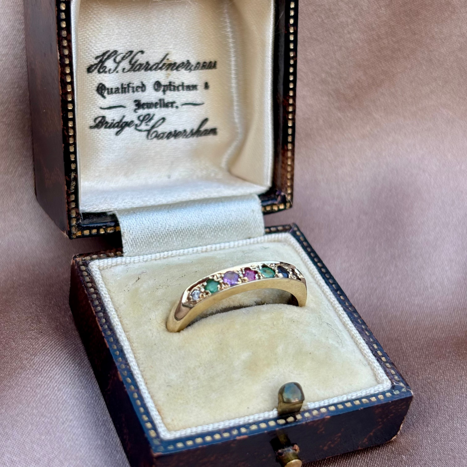 Jewelry box with a ring featuring colorful gemstones on a beige background