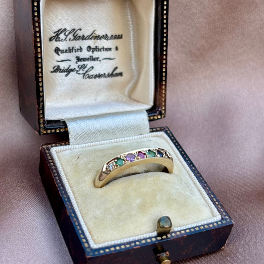 Jewelry box with a ring featuring colorful gemstones on a beige background