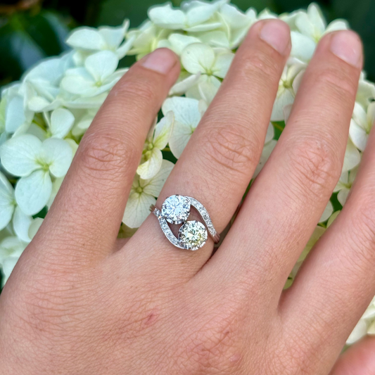 toi et moi crossover platinum Diamond ring on a beige fabric background
